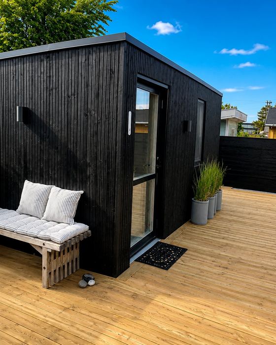 Skur med sort træfacade og terrasse — Pergolahuset