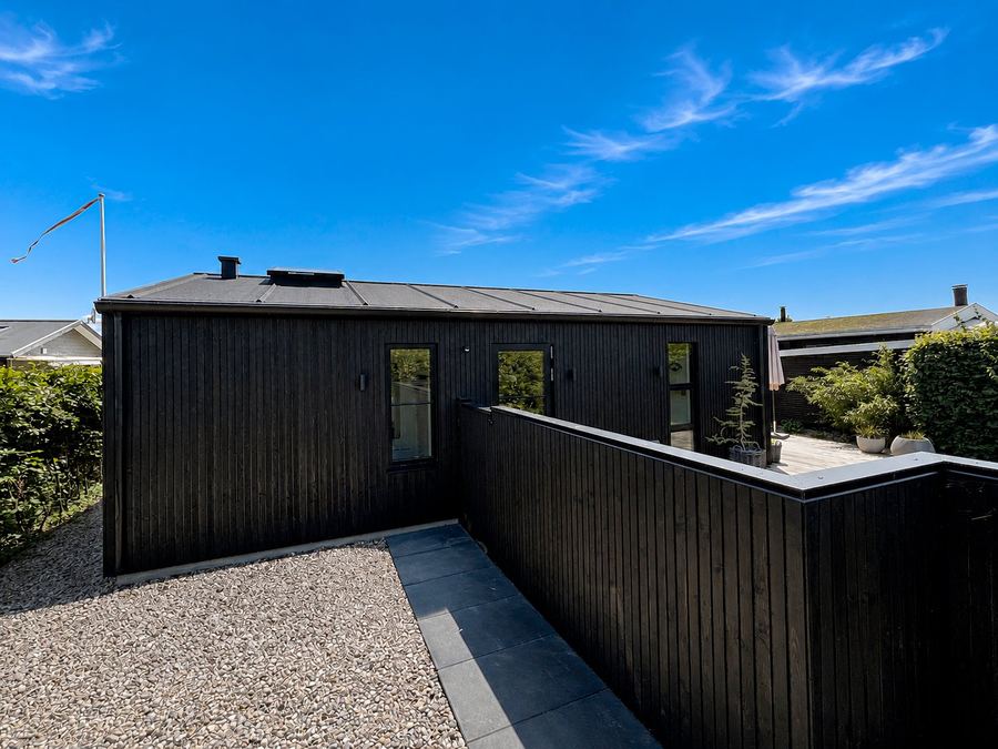 Facade set fra haven med sort tag og sorte tagrender — Fristedet